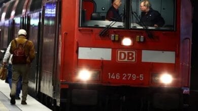 صورة لقطار ألماني حديث يقف في محطة، مع شاشة عرض إلكترونية تظهر رسالة خطأ أو عدم توفر الخدمة بسبب هجوم سيبراني استهدف شركة دويتشه بان.