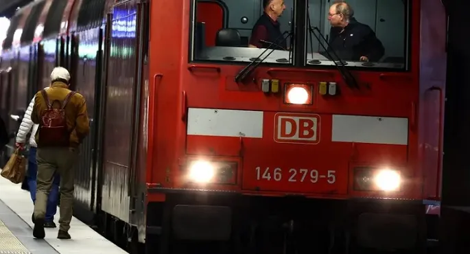 صورة لقطار ألماني حديث يقف في محطة، مع شاشة عرض إلكترونية تظهر رسالة خطأ أو عدم توفر الخدمة بسبب هجوم سيبراني استهدف شركة دويتشه بان.