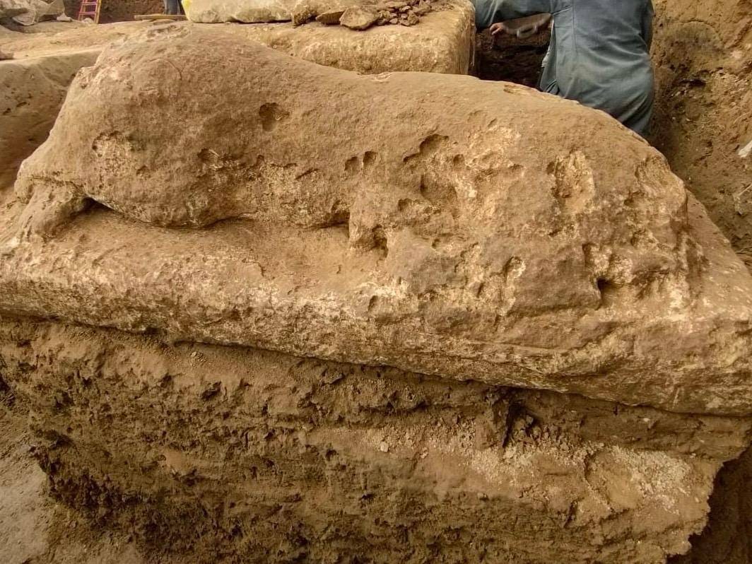 صورة جوية لموقع الحفائر الأثرية بمنطقة تل عزيز في ميت رهينة بالجيزة، تظهر بقايا مبنى حجري قديم يُعتقد أنه جزء من معبد الملك أبريس، وسط اهتمام فريق البعثة الأثرية المصرية-الصينية المشتركة. الموقع يبرز أهمية الحضارة المصرية القديمة.