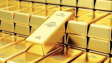 صورة توضيحية لسبائك ذهب متلألئة موضوعة على رسوم بيانية اقتصادية، تعكس تذبذب أسعار المعدن النفيس في الأسواق العالمية وتأثير السياسات النقدية.