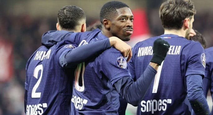 لاعبو باريس سان جيرمان وموناكو يتنافسون على الكرة في ملعب كرة قدم مضاء ليلاً خلال مباراة في دوري أبطال أوروبا، مع جماهير متحمسة في المدرجات.