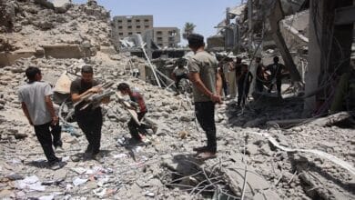 صورة جوية لمركبات مساعدات إنسانية تابعة للأونروا تدخل قطاع غزة، مع خلفية تظهر الدمار في المنطقة، ترمز للأزمة الإنسانية وجهود الإغاثة.