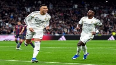 صورة من مباراة كرة قدم تظهر لاعبي ريال مدريد وبنفيكا يتنافسون على الكرة في ملعب النور خلال مباراة بدوري أبطال أوروبا، مع التركيز على شعار البطولة.