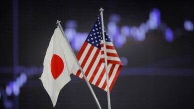 صورة علوية جوية لمشروع ضخم قيد الإنشاء لمحطة طاقة أو مصنع غاز طبيعي، مع خريطة توضيحية لولايات أوهايو وجورجيا وتكساس في الخلفية، ترمز إلى التعاون الاقتصادي بين الولايات المتحدة واليابان.